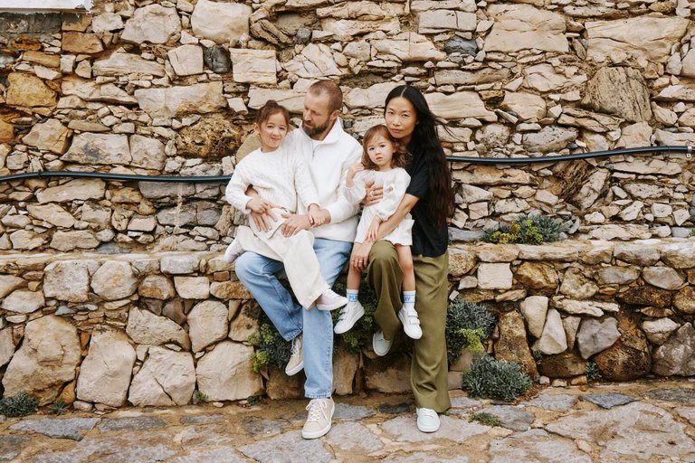 Familie mit 2 Kindern sitzen auf Steinsitz