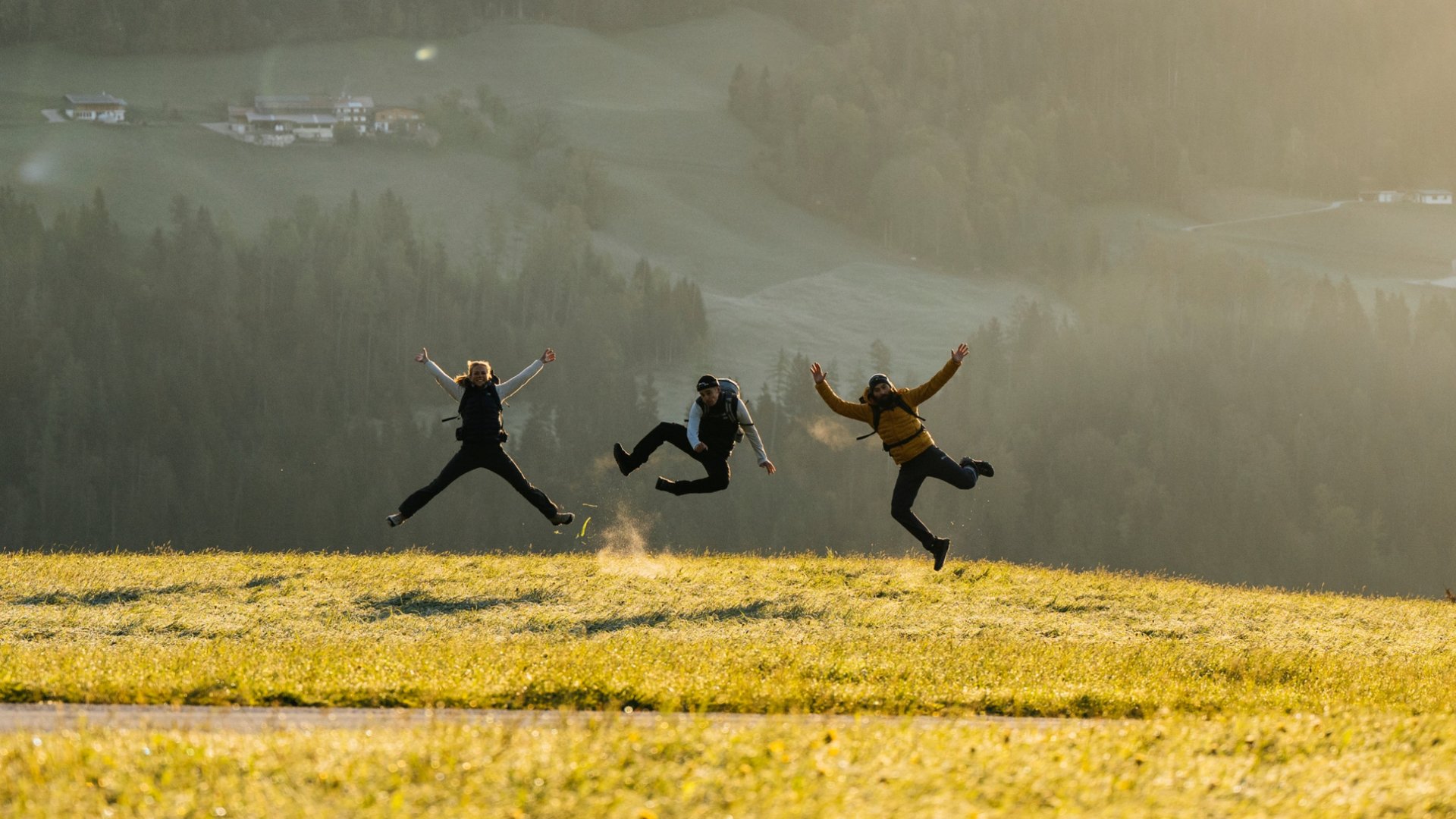 Drei Leute hüpfend auf einem Feld